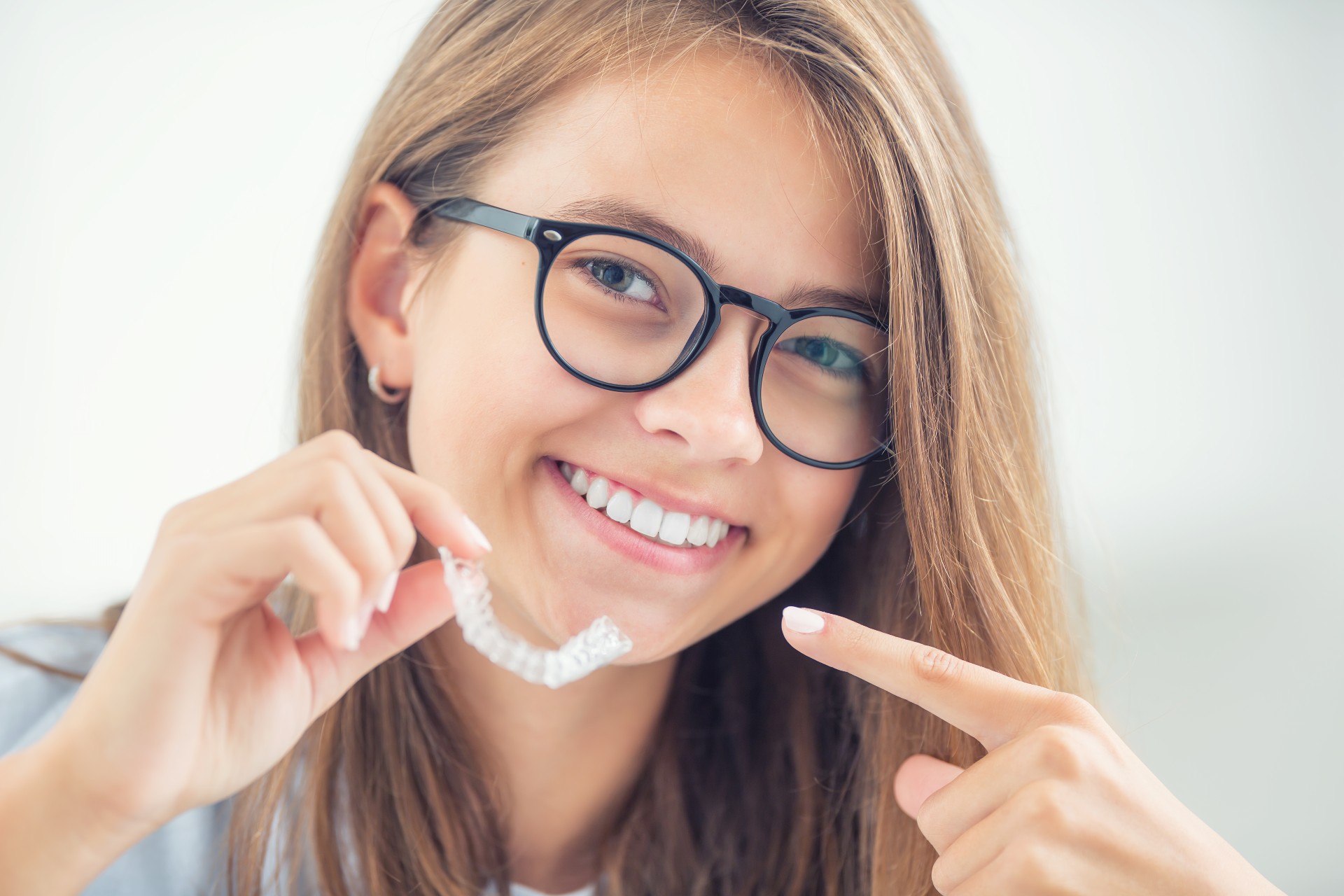 Young kid with Invisalign in hands smiling